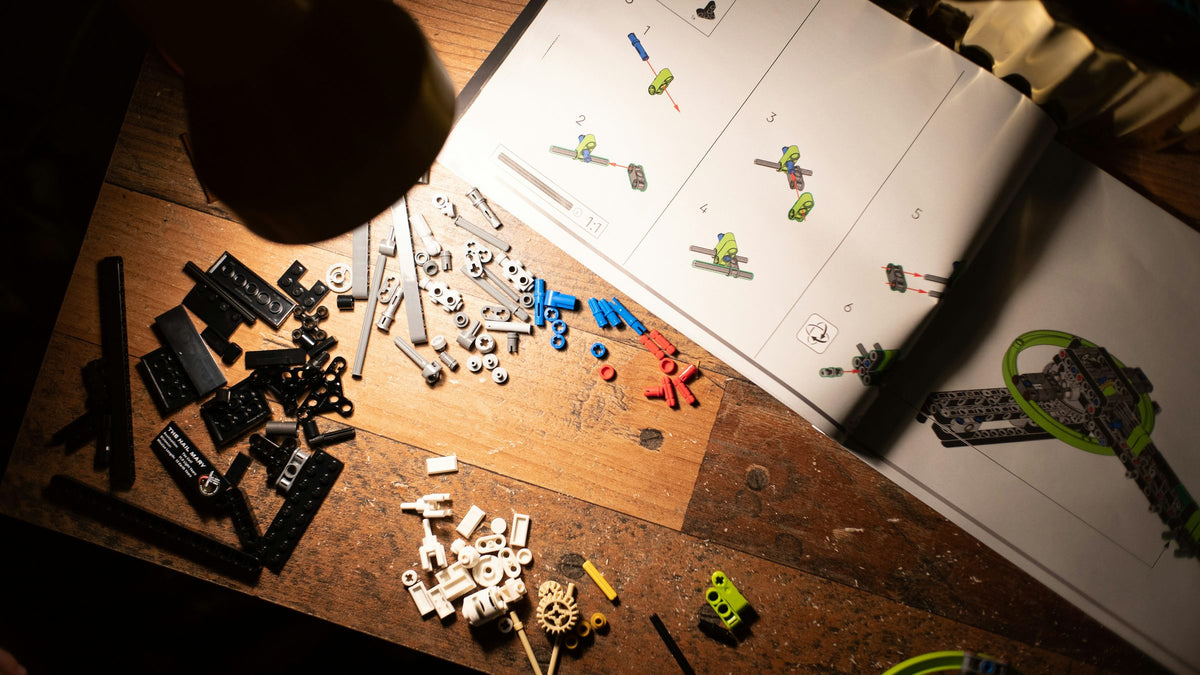 LEGO parts and an instruction booklet on a lamp-lit wooden workbench